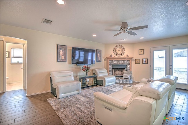 living area featuring visible vents, wood finished floors, a textured ceiling, a fireplace, and recessed lighting