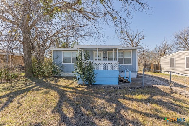 view of front of home featuring covered porch, a front lawn, and fence