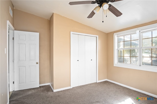 unfurnished bedroom with carpet floors, a closet, vaulted ceiling, and ceiling fan