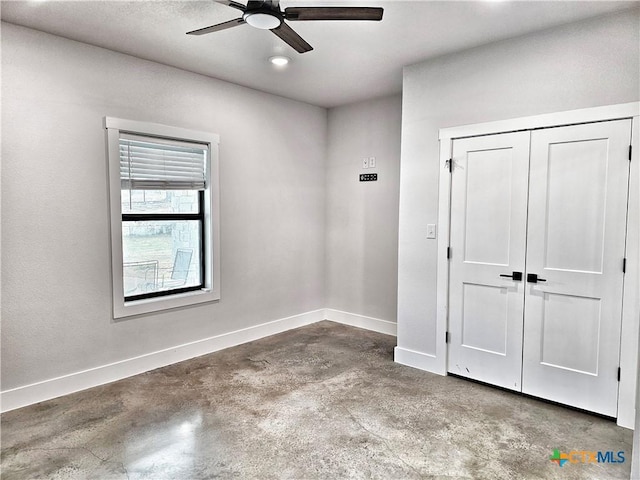 unfurnished bedroom with concrete flooring, a closet, and ceiling fan