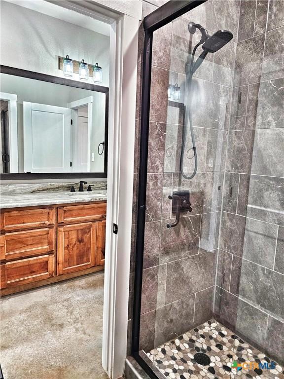 bathroom featuring a shower with door and vanity