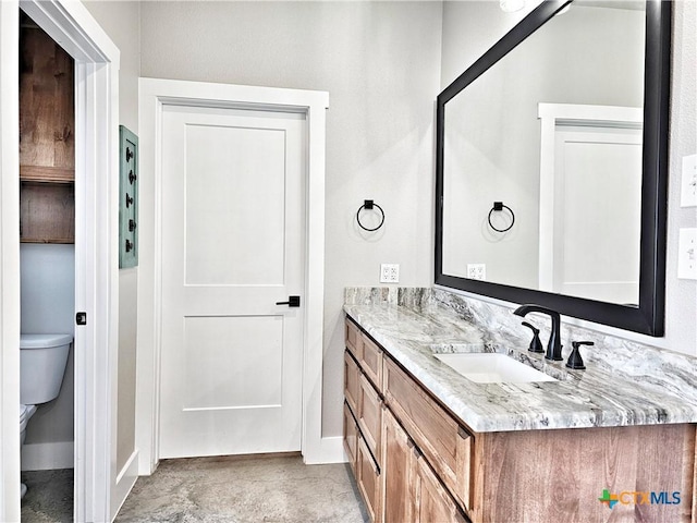 bathroom featuring baseboards, vanity, and toilet