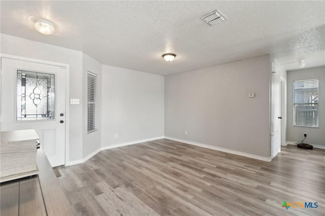 foyer entrance with a textured ceiling and light hardwood / wood-style flooring