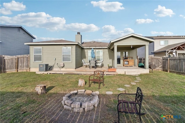 back of house featuring a lawn, a fire pit, a patio area, cooling unit, and a wooden deck