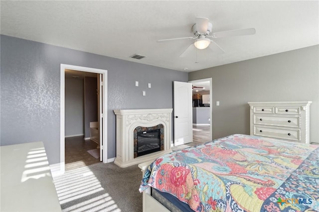 bedroom featuring ceiling fan, a premium fireplace, and dark carpet