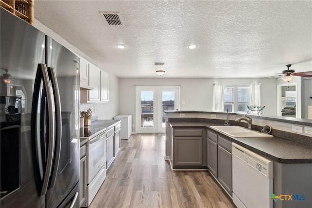 kitchen with sink, white appliances, light hardwood / wood-style flooring, gray cabinetry, and a textured ceiling