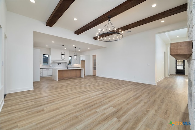unfurnished living room featuring an inviting chandelier, light wood-style flooring, baseboards, and beamed ceiling