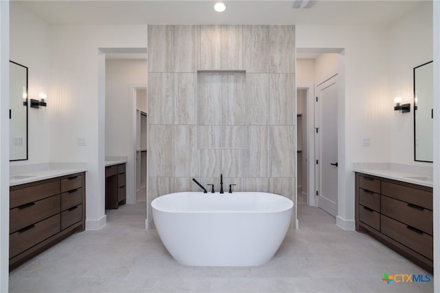 bathroom with tile walls, two vanities, and a freestanding tub