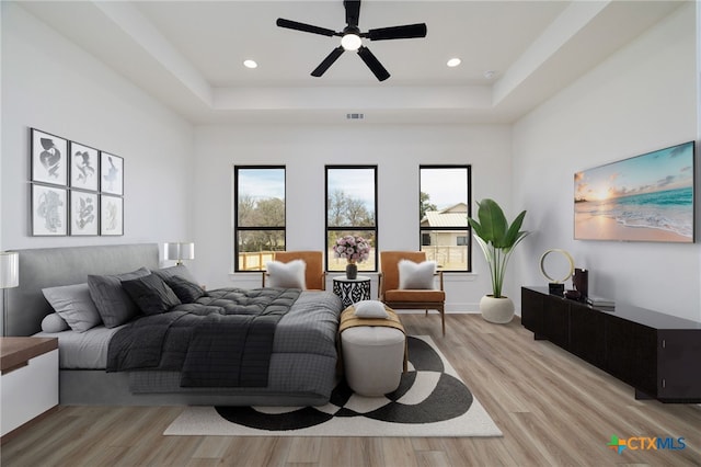bedroom featuring a tray ceiling, visible vents, and light wood-type flooring