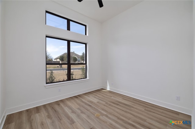 spare room featuring light wood-style floors, a ceiling fan, and baseboards