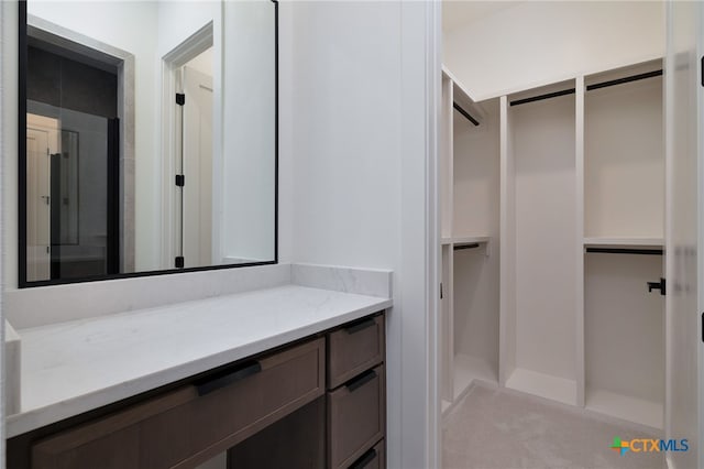 bathroom featuring vanity and a walk in closet
