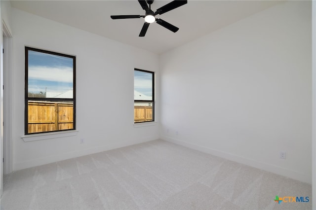 empty room featuring a wealth of natural light, baseboards, carpet, and a ceiling fan