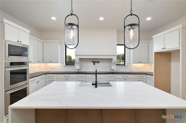 kitchen featuring decorative backsplash, white cabinets, stainless steel appliances, and a sink