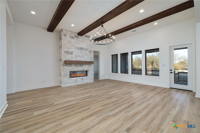 unfurnished living room with baseboards, beamed ceiling, light wood-type flooring, a fireplace, and an inviting chandelier