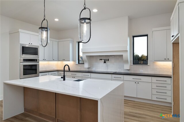 kitchen with decorative backsplash, light wood-style flooring, appliances with stainless steel finishes, and a sink