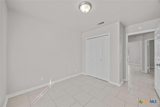 unfurnished bedroom featuring light tile patterned floors, a closet, visible vents, and baseboards