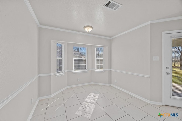 empty room featuring light tile patterned floors, visible vents, ornamental molding, a textured ceiling, and baseboards