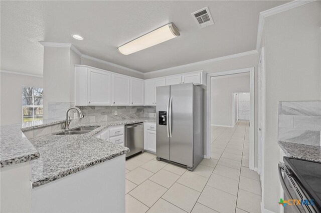 kitchen featuring stainless steel appliances, a sink, white cabinetry, light stone countertops, and tasteful backsplash