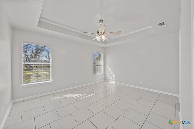 spare room featuring a tray ceiling, visible vents, ceiling fan, and baseboards