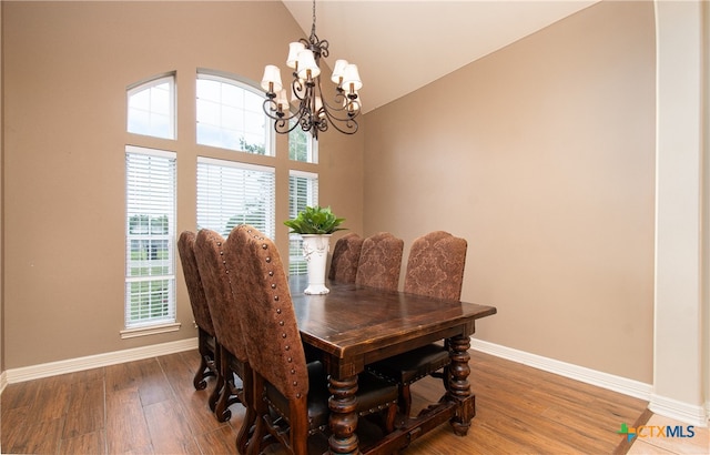 dining area with hardwood / wood-style floors, an inviting chandelier, and high vaulted ceiling