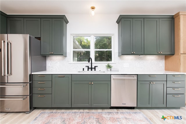 kitchen featuring appliances with stainless steel finishes, sink, backsplash, and light hardwood / wood-style flooring