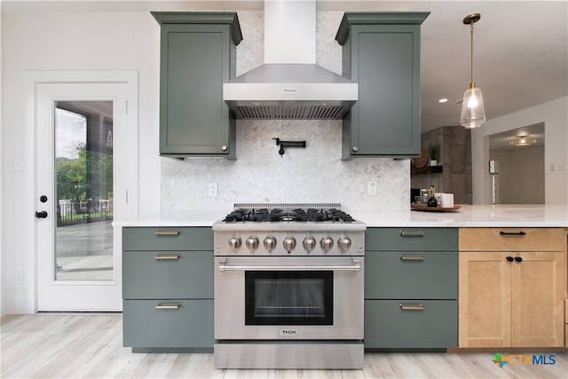 kitchen with light hardwood / wood-style floors, wall chimney range hood, high end range, and decorative backsplash