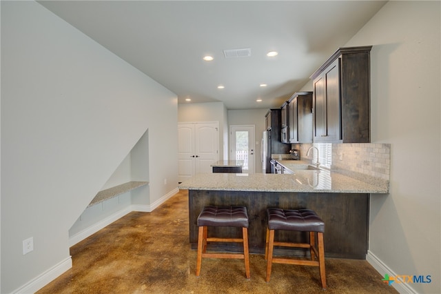 kitchen with stainless steel appliances, backsplash, sink, a breakfast bar area, and kitchen peninsula