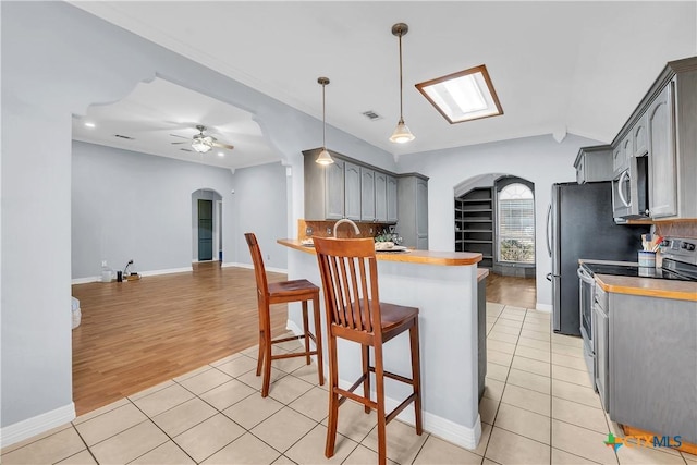 kitchen featuring gray cabinets, appliances with stainless steel finishes, pendant lighting, and light tile patterned floors