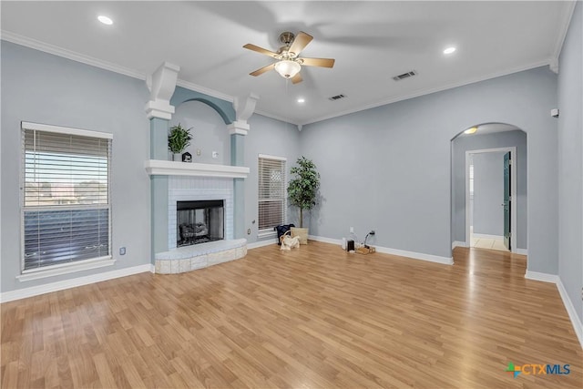 unfurnished living room with crown molding, a brick fireplace, ceiling fan, and light hardwood / wood-style floors