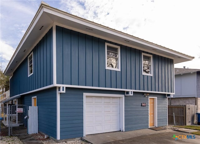 exterior space featuring an attached garage, fence, and board and batten siding