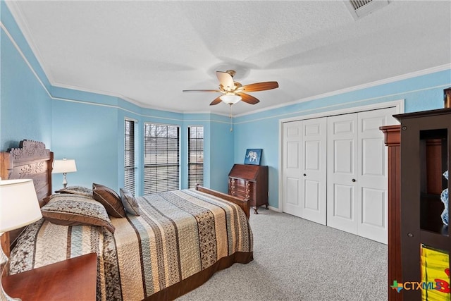 carpeted bedroom with ceiling fan, ornamental molding, a closet, and a textured ceiling