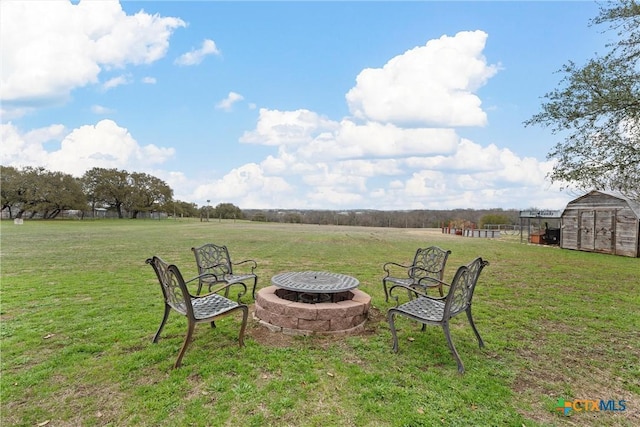 view of yard with a shed, a fire pit, and a rural view