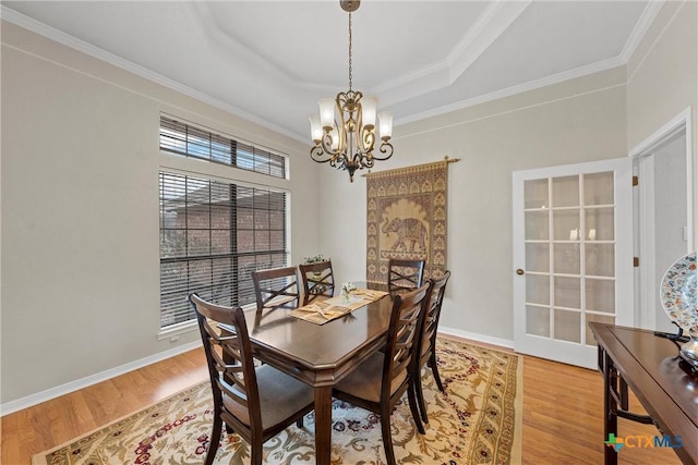 dining room featuring ornamental molding, hardwood / wood-style floors, a notable chandelier, and a tray ceiling