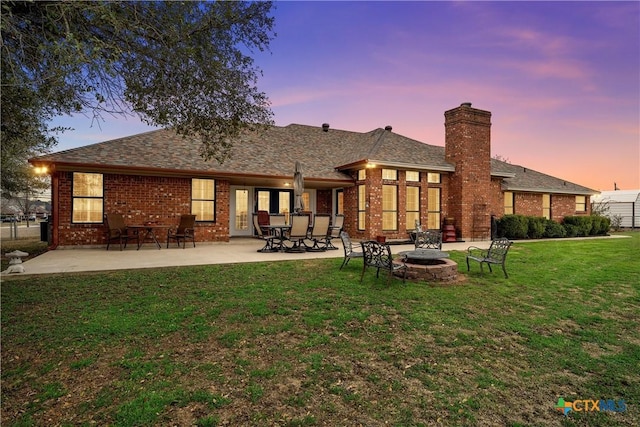 back house at dusk with an outdoor fire pit, a yard, and a patio area