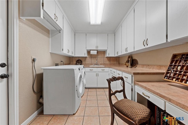 washroom featuring light tile patterned flooring, sink, cabinets, a textured ceiling, and washer and clothes dryer