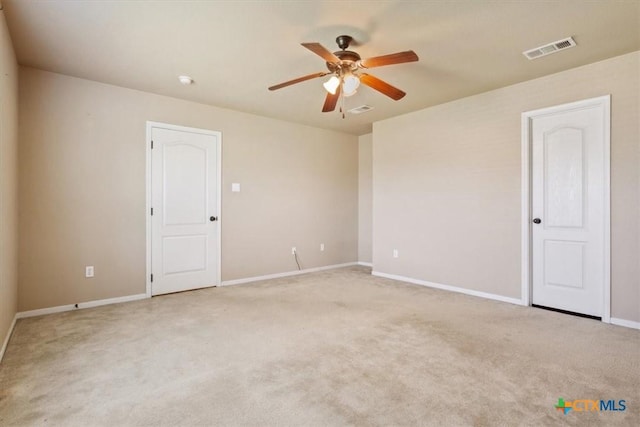 spare room with visible vents, light carpet, baseboards, and ceiling fan