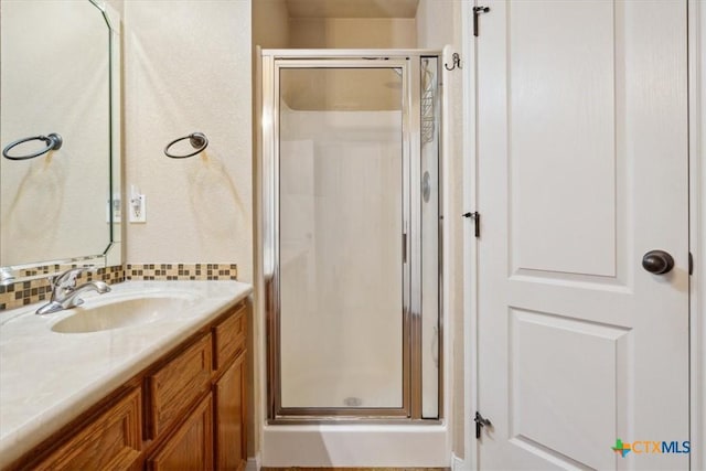 full bathroom featuring vanity, a shower stall, and backsplash