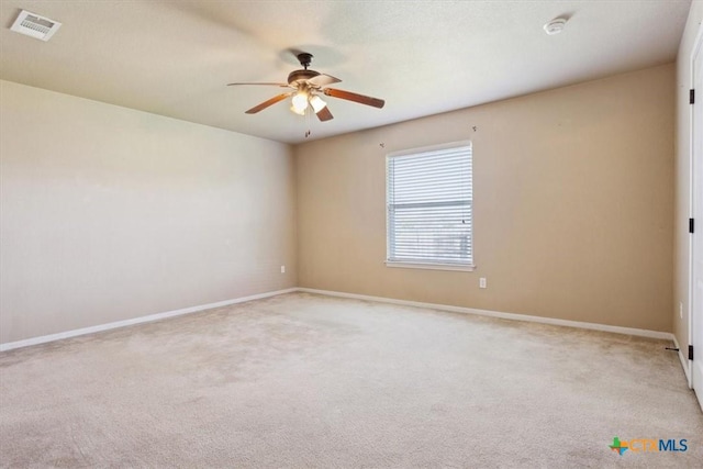 carpeted empty room featuring a ceiling fan, visible vents, and baseboards