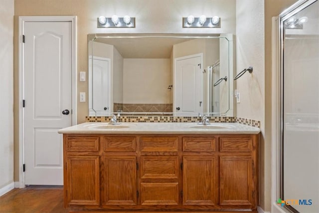 full bath featuring double vanity, a stall shower, tasteful backsplash, and a sink