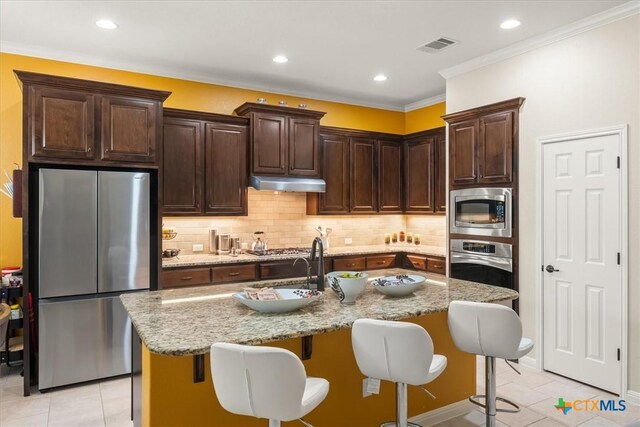 9550 Savannah Ridge Dr Unit 11, Austin, TX 78726 - kitchen with stainless steel appliances, under cabinet range hood, light tile patterned floors, a kitchen bar, and recessed lighting