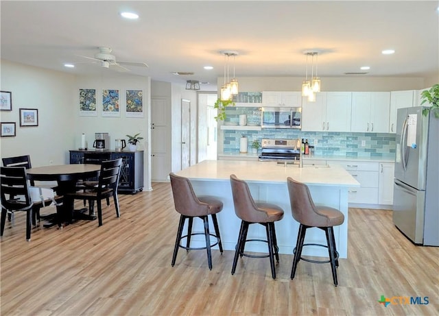4770 Fm 2808, Kempner, TX 76539 - kitchen with appliances with stainless steel finishes, light countertops, a breakfast bar area, tasteful backsplash, and white cabinets