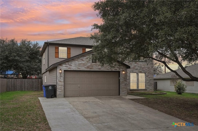 traditional-style house featuring brick siding, concrete driveway, fence, a garage, and a front lawn