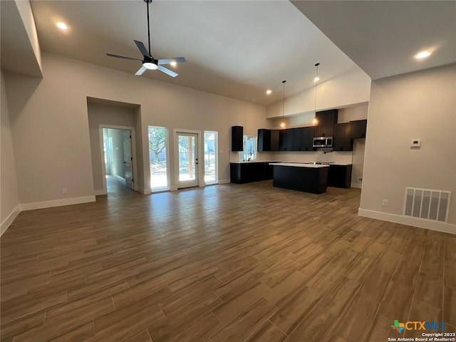 kitchen with open floor plan, stainless steel microwave, visible vents, and a center island