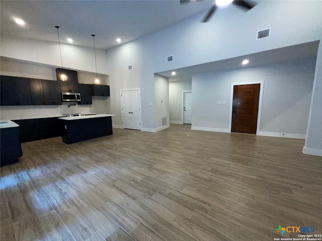 kitchen with stainless steel microwave, visible vents, open floor plan, a kitchen island, and wood finished floors