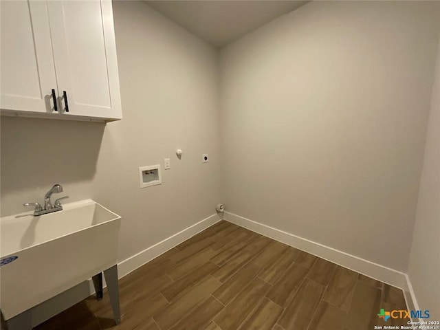 washroom with a sink, baseboards, cabinet space, dark wood finished floors, and electric dryer hookup