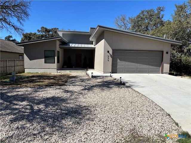 view of front of home featuring metal roof, a garage, driveway, stucco siding, and a standing seam roof