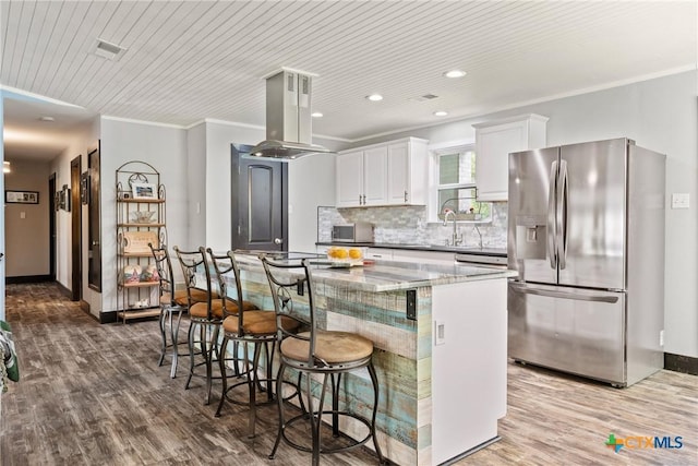 1215 Amanda, Canyon Lake, TX 78133 - kitchen with stainless steel fridge with ice dispenser, island range hood, wood finished floors, white cabinetry, and recessed lighting