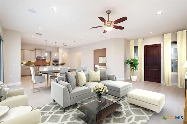 living area featuring light wood-style flooring, visible vents, baseboards, and recessed lighting