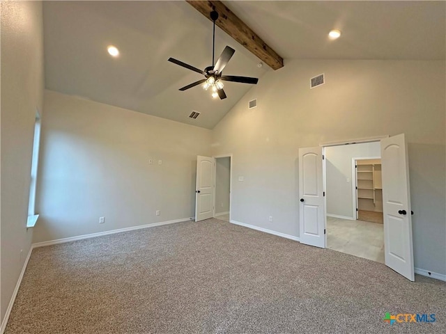 unfurnished bedroom featuring light colored carpet, beam ceiling, high vaulted ceiling, and a spacious closet