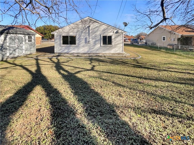 back of house featuring a lawn and an outdoor structure